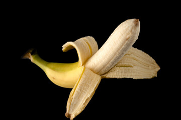 One Banana, half peeled, on a black background isolated