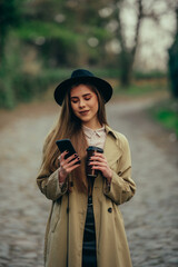 Woman using smartphone and drinking coffee