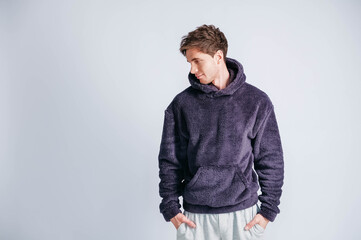 Portrait of a young man in purple sweatshirt with hood on a white background. Copy, empty space for text