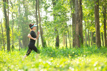 Healthy athletic woman running in the Nature park to be more healthy. Healthy and Lifestyle concept. On Green Nature background.