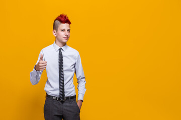 Teenager boy over isolated yellow background approving doing positive gesture with hand, thumbs up smiling and happy for success. Winner gesture