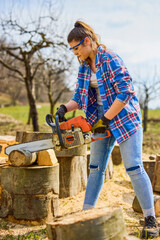 Young Woman using chainsaw to cut a log for firewood.