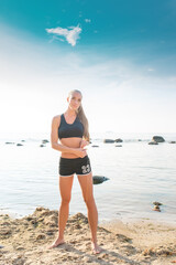 young beautiful sportswoman doing exercises on beach with measuring tape