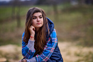 portrait of a young woman wearing a hooded jacket with nature in the background