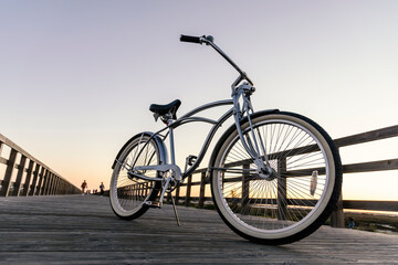 Fototapeta na wymiar New vintage bike parked in the middle of the wooden boardwalk at sunset