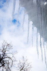 Icicles on the roof against the blue sky. Winter concept, vertical arrangement