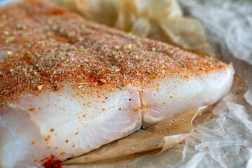 Raw Halibut Fillet with Cajun Spice Rub: An uncooked fish fillet that has been rubbed in spices