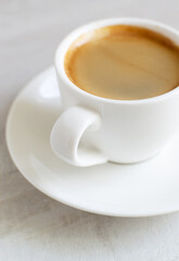 Fragrant espresso in a white cup and saucer. Morning of tradition. Homemade coffee making concept. Vertical orientation. Close-up.