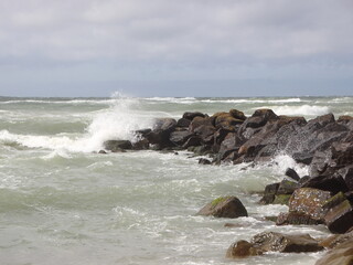Solid breakwater rocks with cloudy ocean horizon