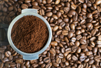 Ground coffee in a horn among aromatic beans. Home coffee making concept. Horizontal orientation. Top view. Close-up.
