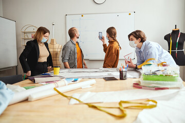 Tailors standing near table and taking picture of whiteboard