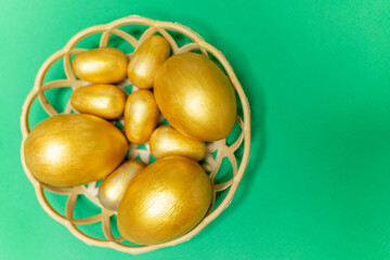 Golden eggs in a basket on a green background. Happy Easter greeting card. Green monotone...