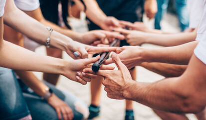 Close-up of the hand of people who are holding 1 stick all together. Team building event