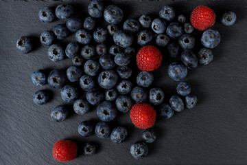 Top view of Healthy berries. Blueberries and Raspberries over a black slate and dark background