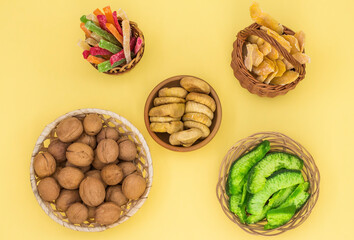 nuts and dried fruits in round plates and baskets on a yellow background