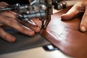 Fototapeta na wymiar Working process of leather craftsman. Tanner or skinner sews leather on a special sewing machine, close up.worker sewing on the sewing machine