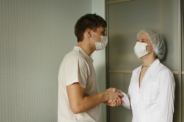 Obraz premium Female doctor greets and shakes hands with male patient during meeting in medical office.