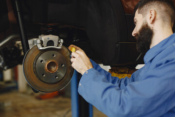 Man replaces wheel in car in garage on hoist