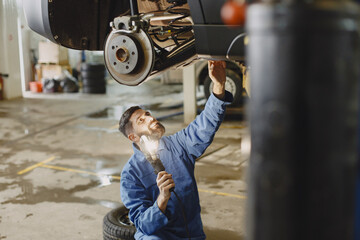 Checking car for serviceability in garage with tools on hoist