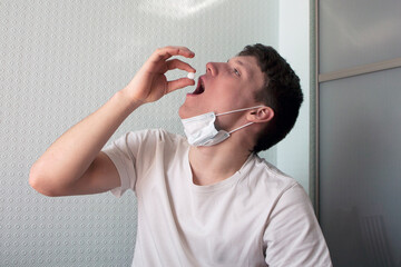 young man puts a pill in his mouth