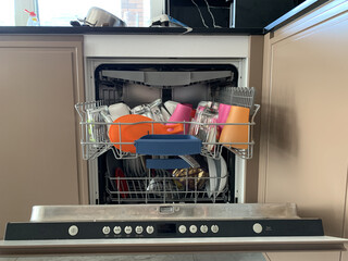 The dishwasher is loaded with dishes. Dishes in an open dishwasher. Kitchen appliances for dishes.