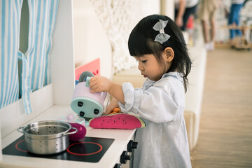 A toddler girl is playing kitchen toy.