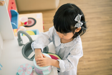 A toddler girl is playing kitchen toy. - 424819318