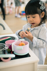 A toddler girl is playing kitchen toy. - 424819324