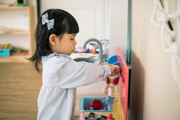 A toddler girl is playing kitchen toy. - 424819748