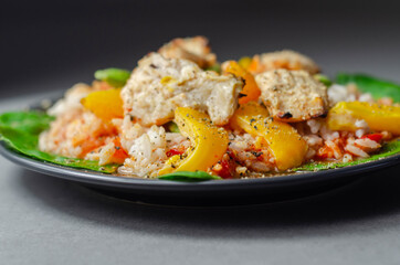 Cooked chicken breast pieces with peppers, sugar snap peas, and baby leaf spinach in a spicy sweet and sour sauce with fragrant rice