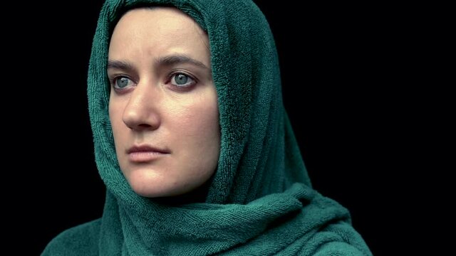 Portrait of woman's head wrapped with green towel over black background