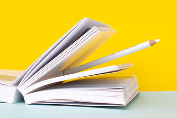 a pencil between the pages of the book on a yellow background