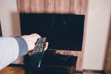 the man watches TV and holds a remote control in her hands