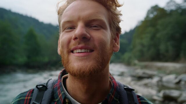 Hiker standing in mountain landscape. Redhead man looking at camera outdoor