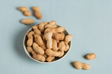 Pile of Peanuts in a bowl on a light blue background