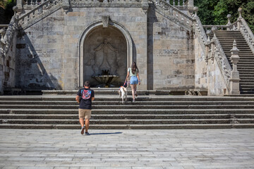 Fototapeta na wymiar View of young couple climbing the stairs of Lamego Cathedral with labrador guide dog