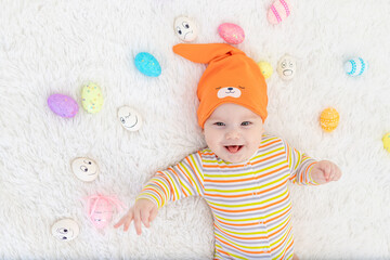 baby boy in orange clothes lying with Easter eggs, cute funny smiling little baby. The concept of Easter.