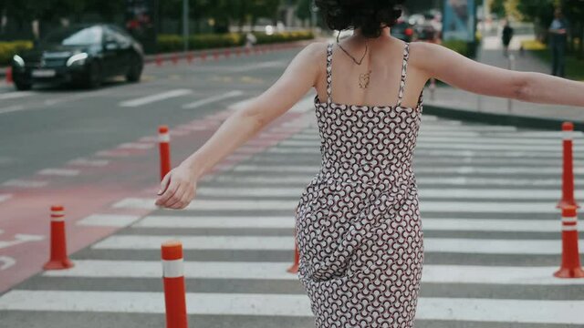 Happy girl running across the street on a pedestrian crossing