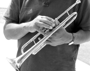 Male trumpet player holding his horn outside.