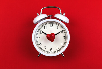 Concept of time and love, red heart and alarm clock on a red background