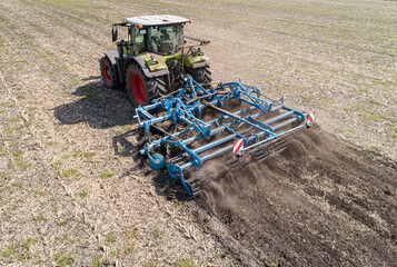 Ackerbau ,  Traktor mit Grubber bei der Bodenbearbeitung aus der Vogelperspektive -...