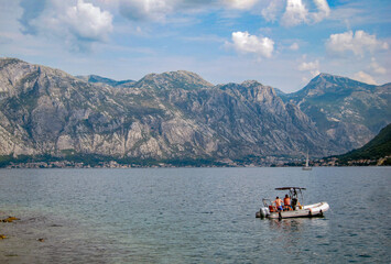 Bay of Kotor on a sunny evening with two unrecognizable men in an inflatable motor boat. Mountains and sea. Beautiful nature.