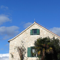 Traditional Mediterranean house with wooden window shutters and flowers.