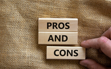 Pros and cons symbol. Wooden blocks with words 'Pros and cons'. Beautiful canvas background, businessman hand. Business, pros and cons concept, copy space.