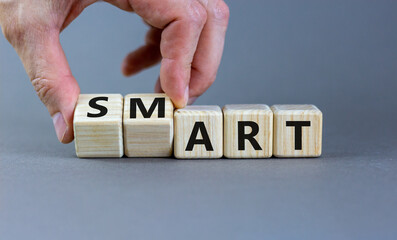 Smart art symbol. Businessman turns cubes and changes the word 'smart' to 'art'. Beautiful grey table, grey background. Business and smart art concept, copy space.