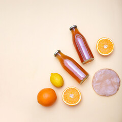 Two bottles of kombucha tea, scoby and citrus fruits for additional flavors on yellow pastel background. Orange, lemon. Healthy fermented drink. Flatlay mockup