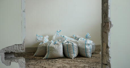 Pile of bags with construction debris stands on floor in building room