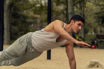 hombre musculoso haciendo deporte, deportista entrenando en el parque, hombre con camiseta blanca
