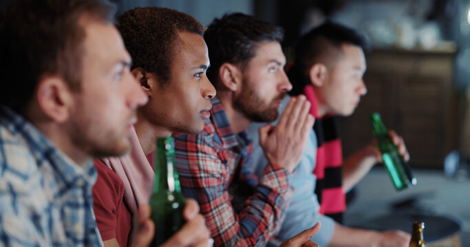 Group Of Funny Male Friends Multi-ethnic Men Football Fans Gathering At Night Together Watching Soccer Gameplay Competition Match On TV.