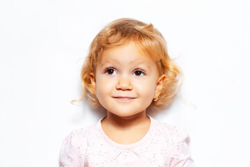 Studio portrait of cheerful child girl with curly blonde hair, looking up on background of white color.